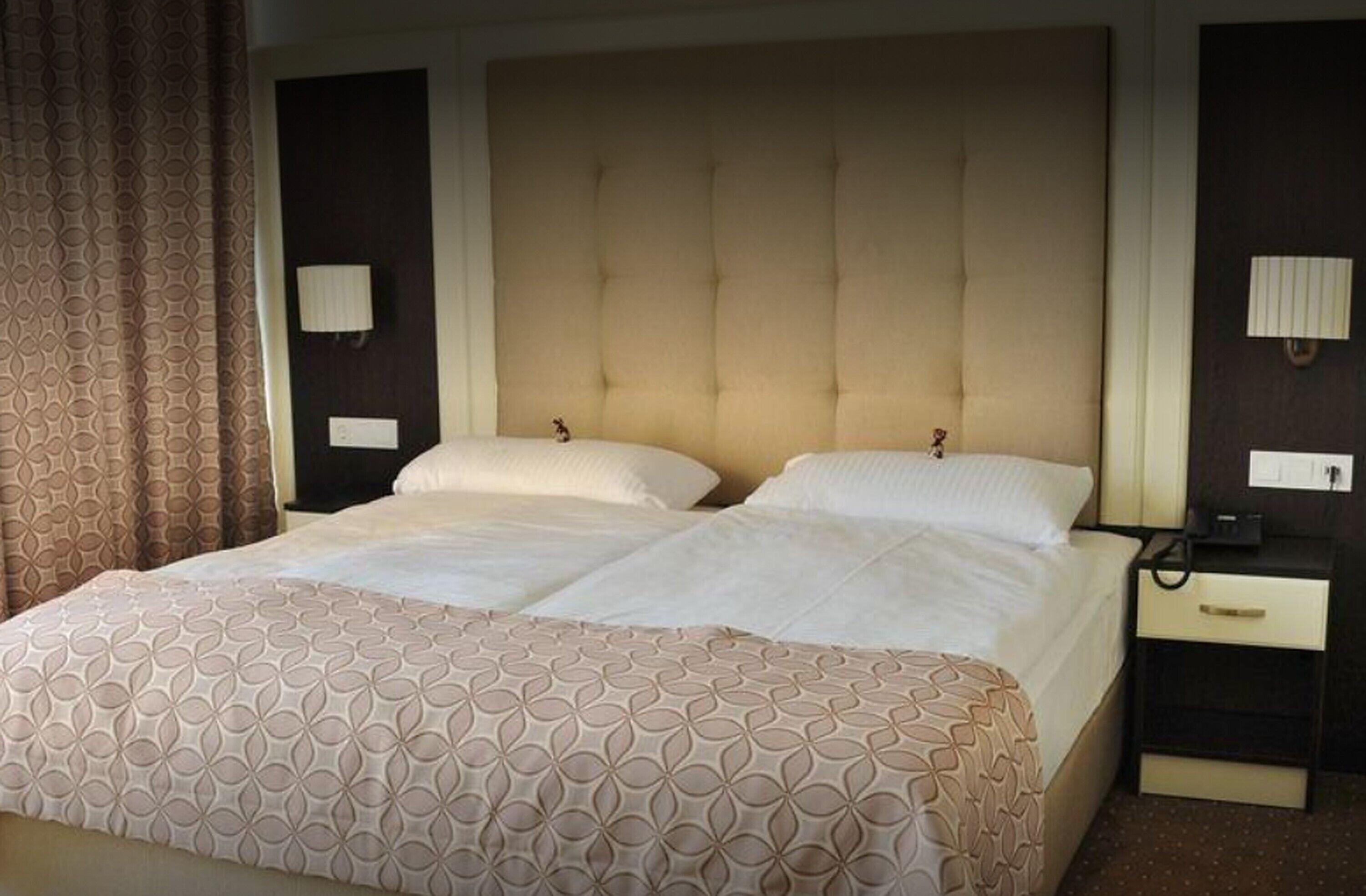 Une chambre d’hôtel avec un grand lit, deux tables de chevet et une tête de lit.