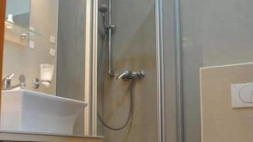 Un baño moderno con ducha de vidrio, lavamanos y retrete.