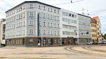 A multi-story hotel with a prominent sign, a corner location, and a tram line nearby.