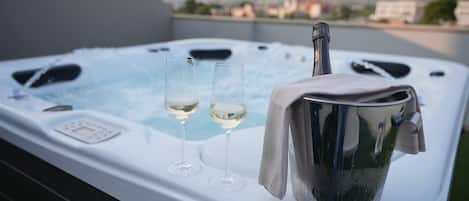 A hot tub with two glasses of white wine and a bucket of ice.