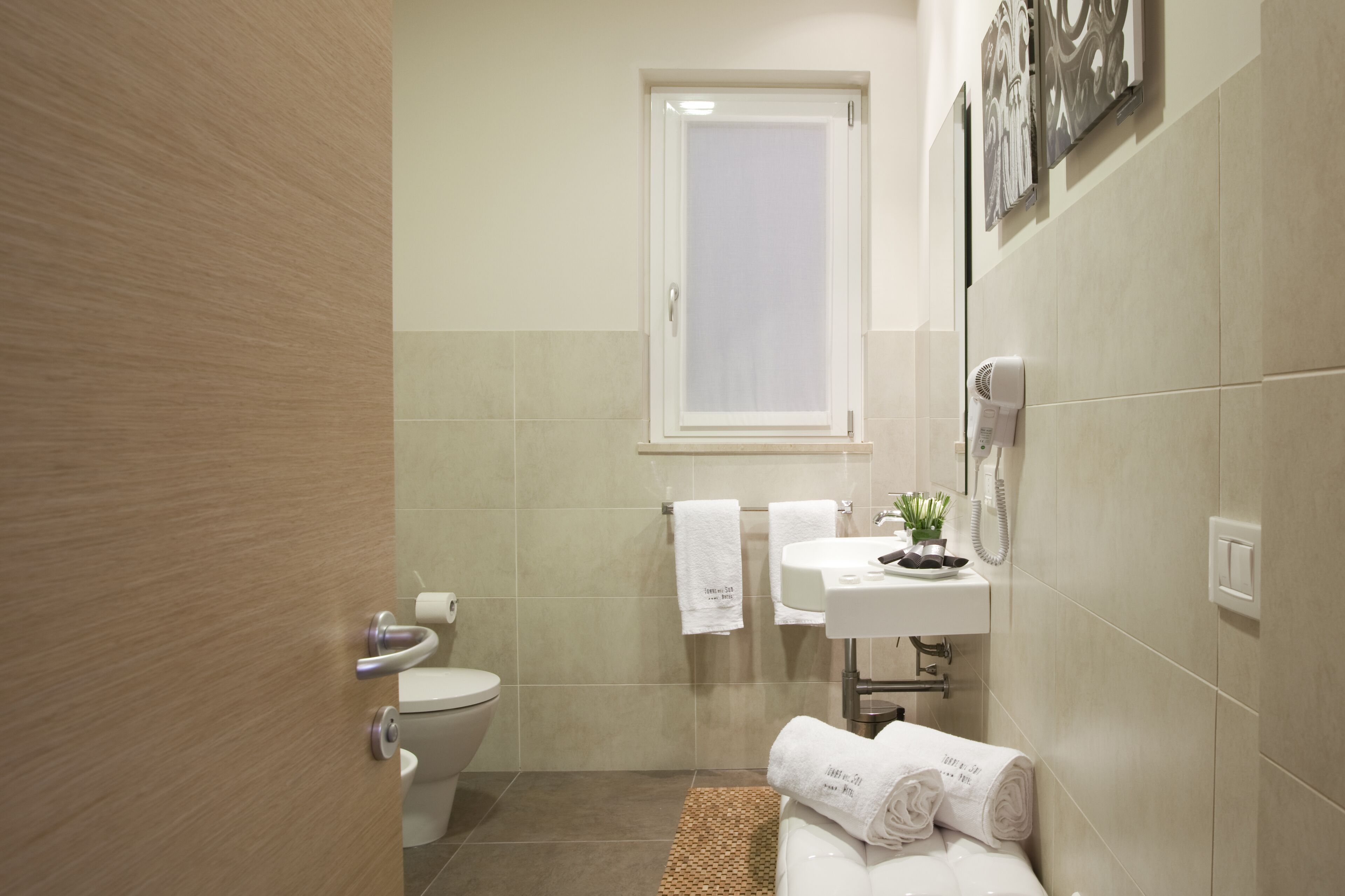 Un baño moderno con inodoro, lavamanos y una ventana pequeña.