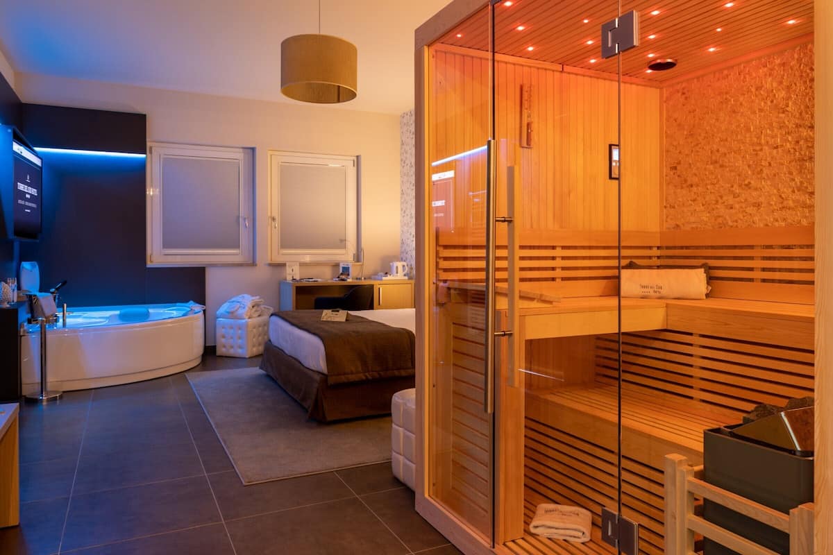 A modern spa room with a sauna, a massage table, and a separate shower area.