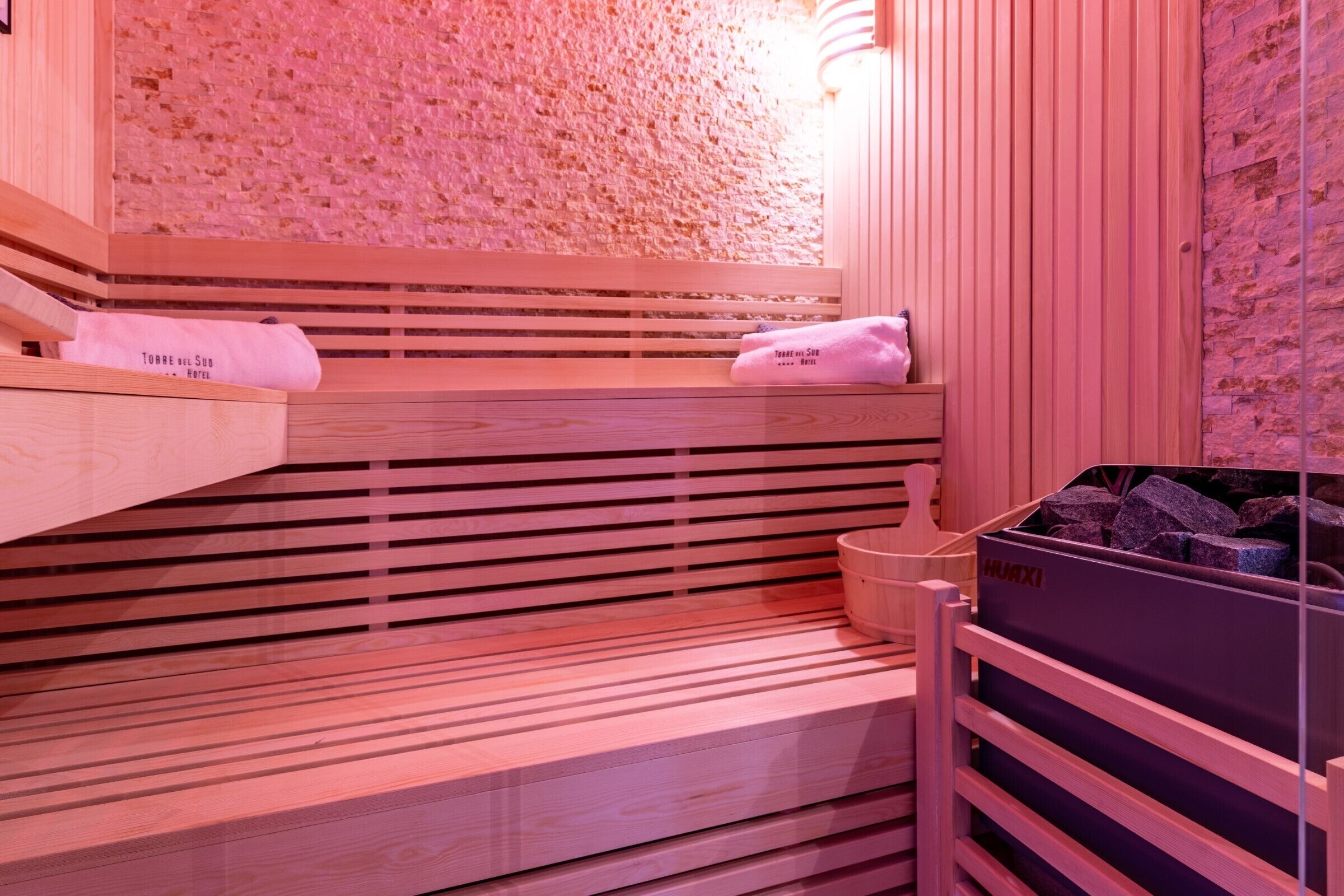 A wooden sauna with benches and a stone wall.