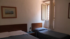 A room with two beds, a nightstand, a lamp, a framed picture on the wall, and a window with curtains. - Hotel Pomezia (Rome)