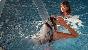 Una persona en una piscina con agua saliendo de una tubería.