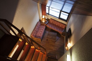 A staircase leading to a seating area with a window, a lamp, and a small table.