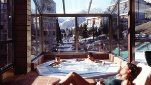 Habitación de hotel moderna con un amplio ventanal que ofrece vistas a una montaña nevada y un paisaje urbano.