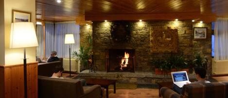 A cozy lobby with a stone fireplace, wooden ceiling, and comfortable seating areas.