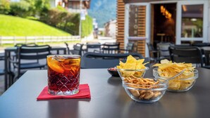 A table with a drink, chips, and nuts.