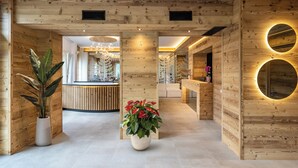 A wooden reception area with a reception desk, potted plants, and a circular mirror on the wall.