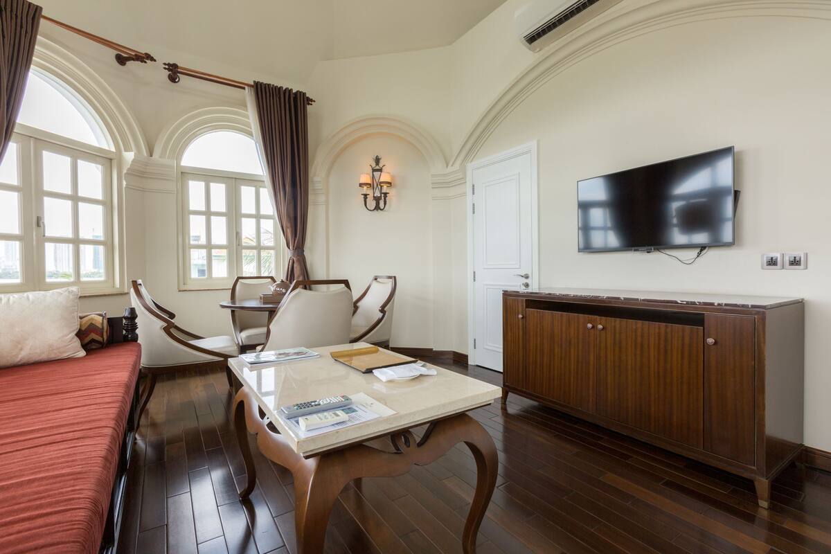 Une chambre d’hôtel comprenant un lit, une table à manger, des chaises, un téléviseur et une armoire en bois.