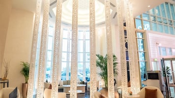 Un hall amplio con techos altos, muebles modernos y columnas decorativas.