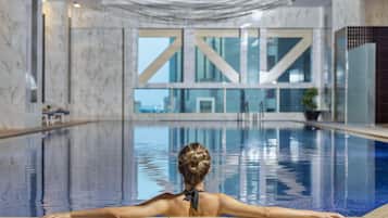 A person relaxing in a swimming pool with a view of a building with large windows.