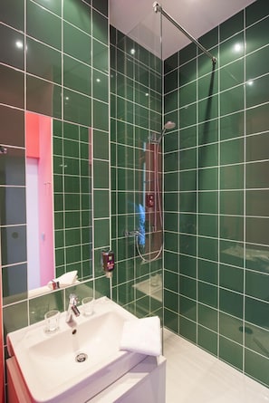 A modern bathroom with green tiles, a white sink, and a handheld showerhead. - ibis Styles Frankfurt City (Frankfurt)