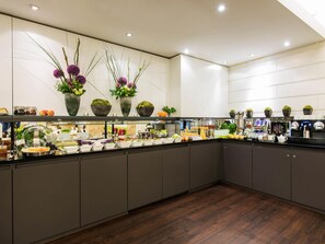 A modern kitchen with a buffet setup, including various food items and a coffee station.