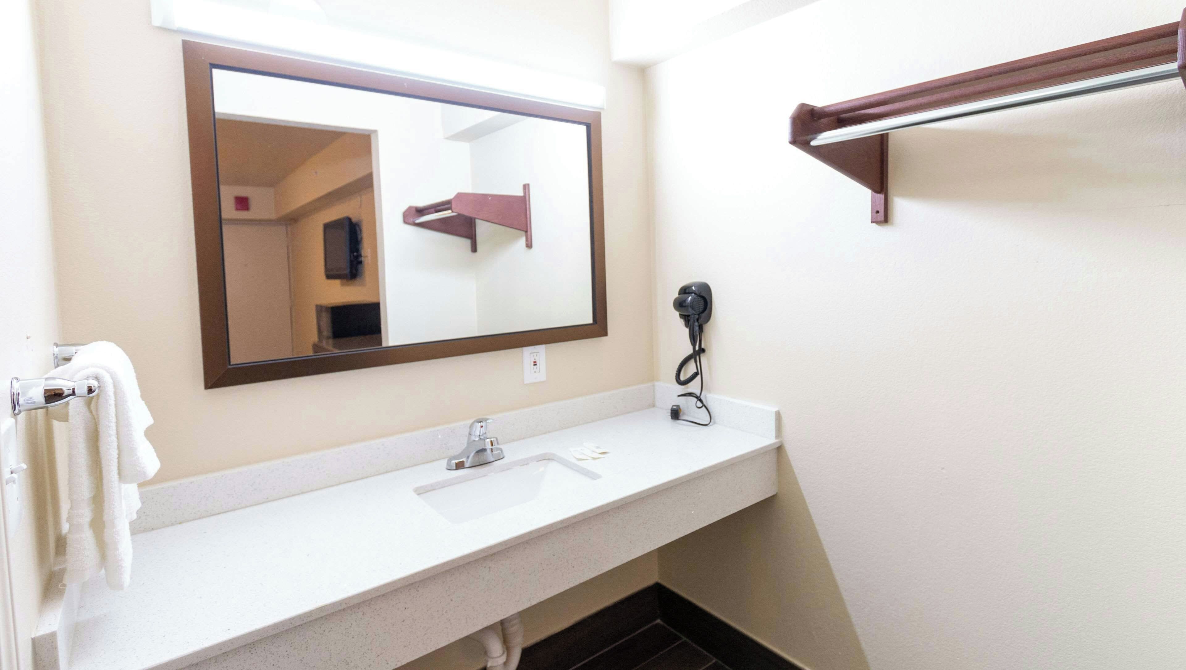 A bathroom with a white sink, a mirror, a hairdryer, and a towel rack.