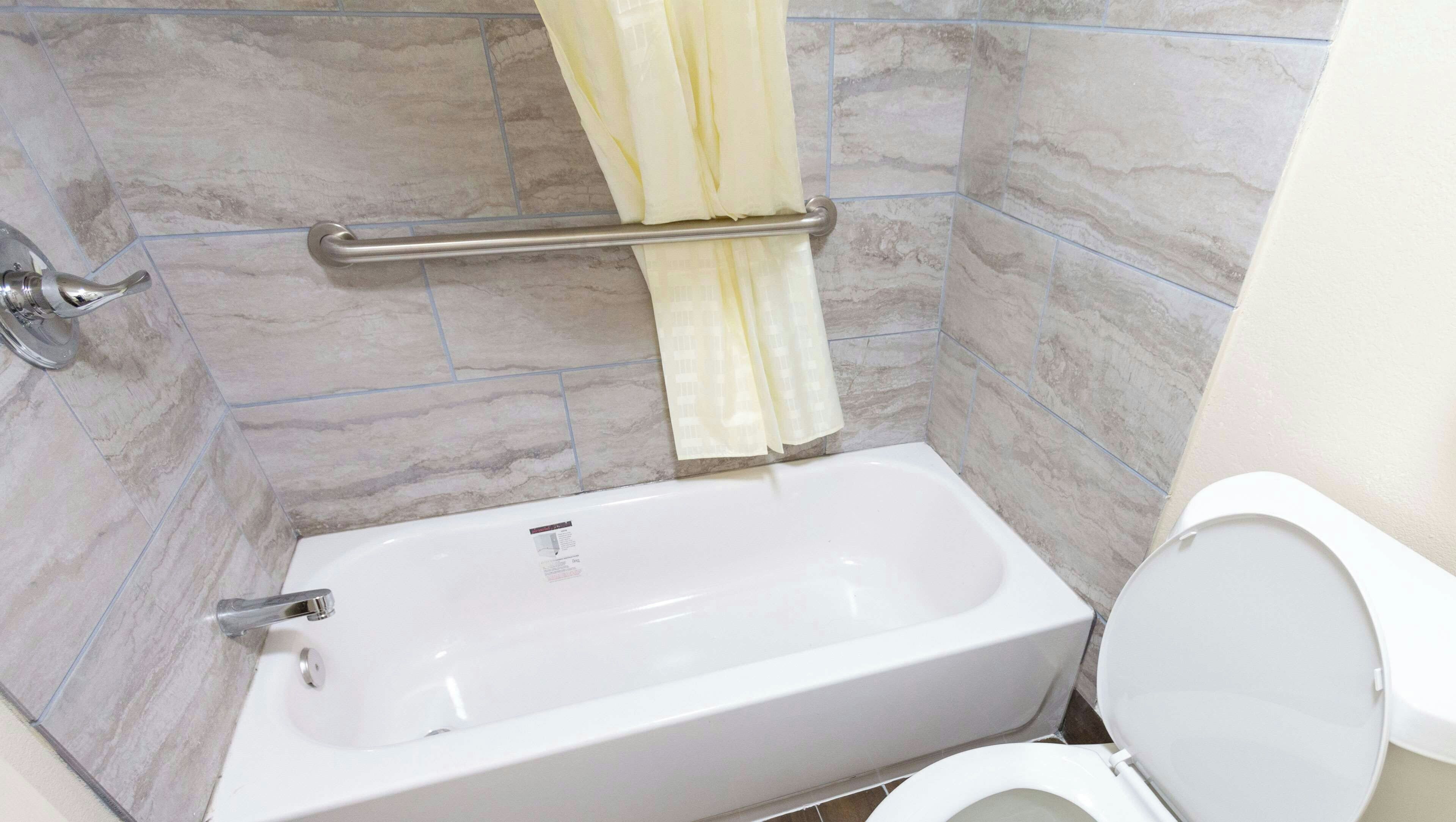 Un baño con bañera, inodoro y cortina de ducha.