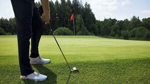 A golf course with a flag, a golf club, and a golf ball on the grass. - Magnuson Extended Stay and Suites Airport Hotel (Irving)