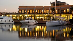 A marina with several yachts docked in front of a building with multiple balconies and large windows. - MarinaPlace Resort & Spa (Genoa)