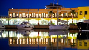 A marina with boats docked in front of a brightly lit building with multiple balconies and large windows. - MarinaPlace Resort & Spa (Genoa)