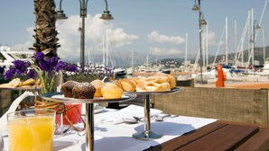 A table with pastries and a glass of orange juice, overlooking a marina with boats and a clear sky. - MarinaPlace Resort & Spa (Genoa)