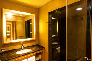 A modern bathroom with a large mirror, a sink, and a glass-enclosed shower.