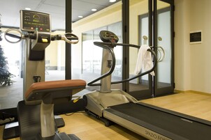 Ένα γυμναστήριο με όργανα για καρδιαγγειακή άσκηση, έναν διάδρομο και έναν τοίχο με καθρέφτες.