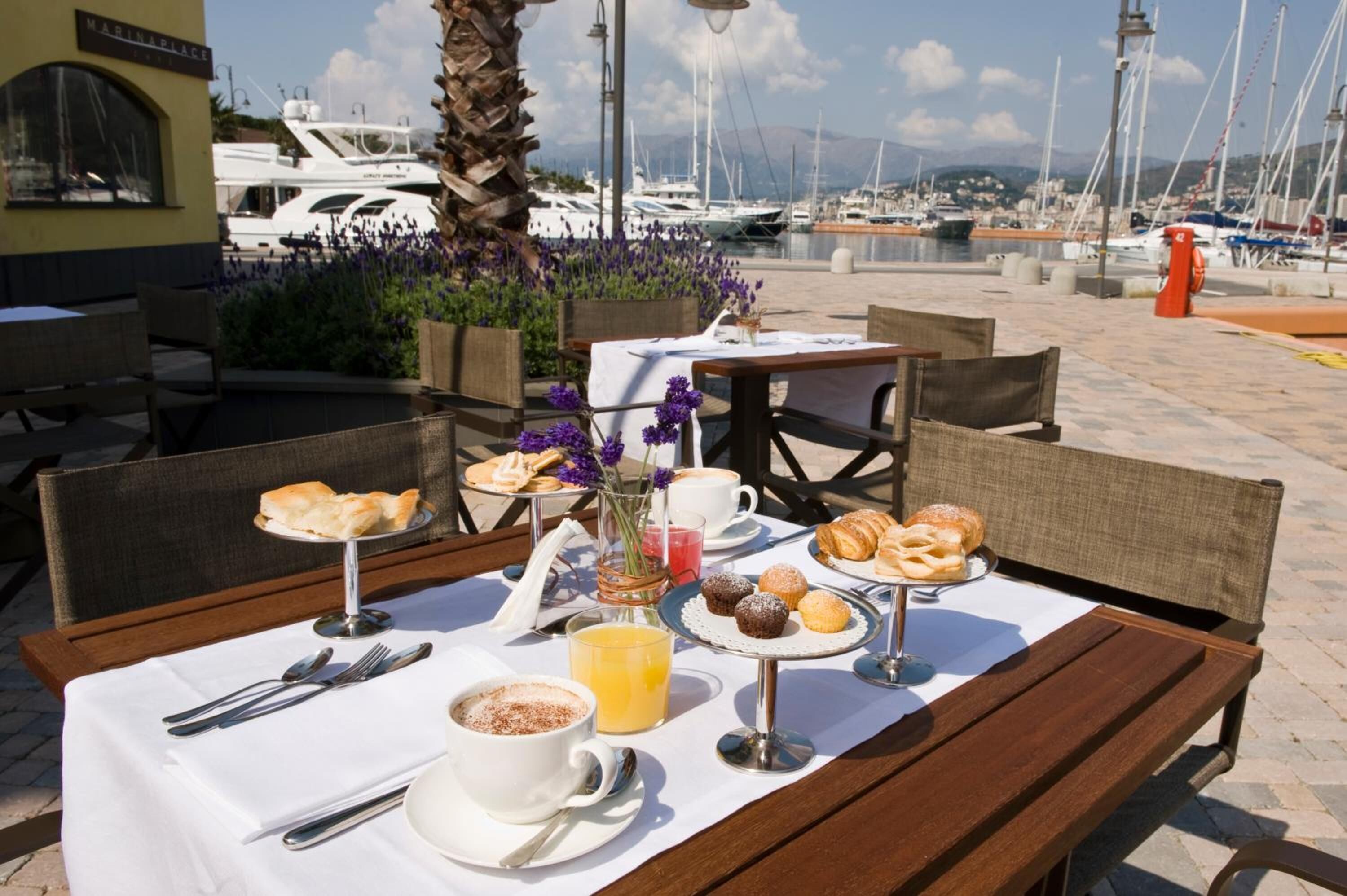 Ein Essbereich im Freien mit Tisch, gedeckt für ein Frühstück, einschließlich Croissants, Muffins und einem Kaffeegetränk.