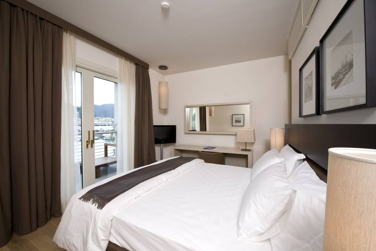 A hotel room with a bed, a desk, a television, and a window with curtains.