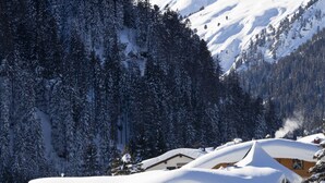 A snow-covered lodge with multiple windows and balconies, surrounded by snow-laden trees and mountains. - Der Waldhof (Sankt Anton am Arlberg)
