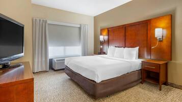 A hotel room with a large bed, a flat-screen TV, a bedside table, and a wall-mounted light fixture.