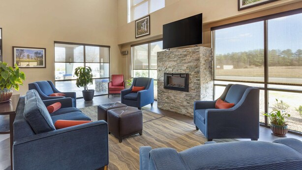 Amplia sala de estar con varios sofás y sillones, chimenea de piedra y ventanas amplias que ofrecen vistas al exterior.