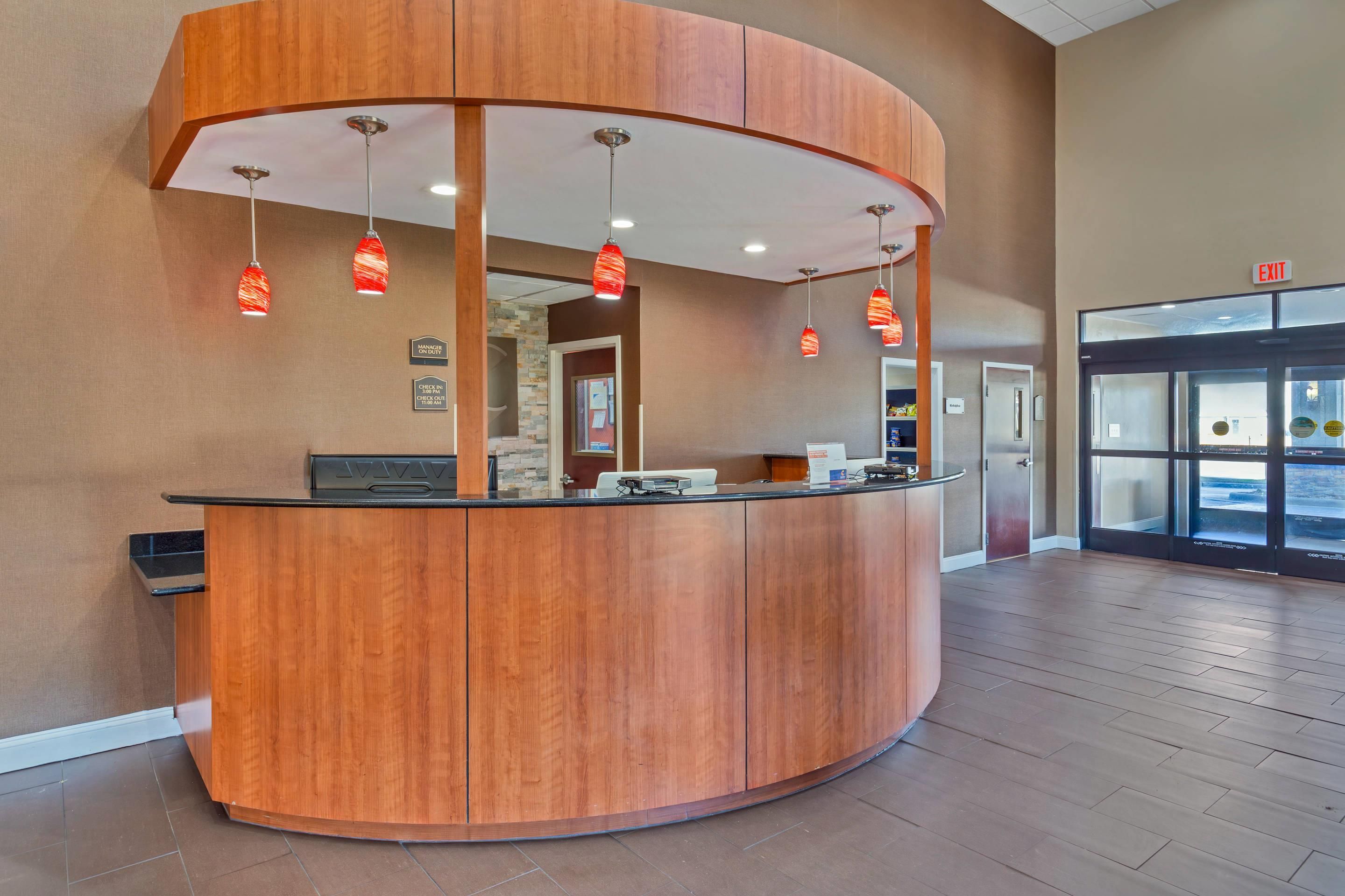 A reception desk with a curved design, multiple pendant lights, and a glass door leading to the entrance.