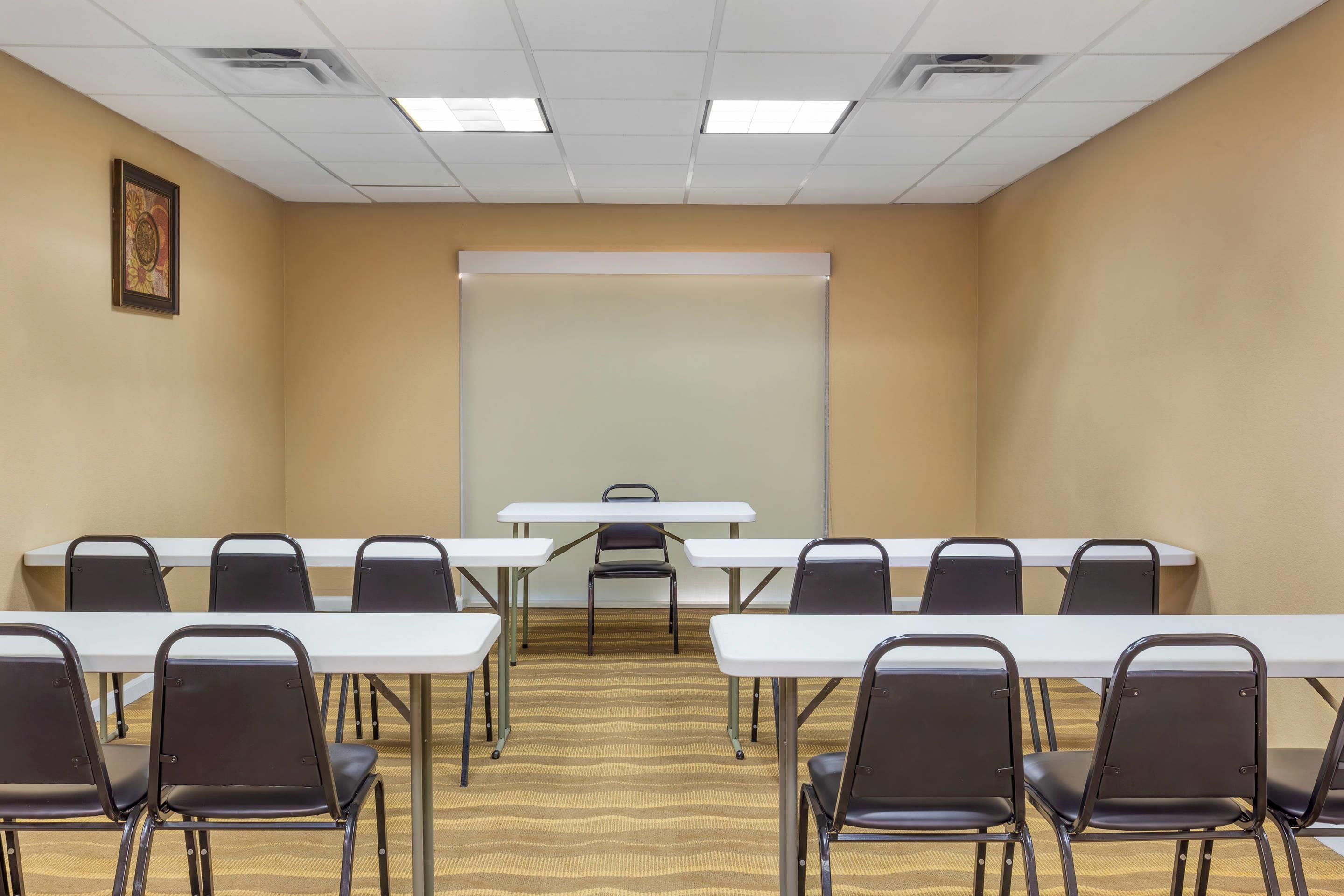A conference room with a whiteboard, tables, and chairs arranged for meetings.