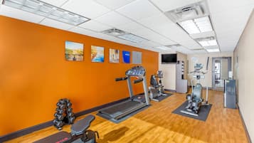 Un gimnasio con cintas de correr, elípticas y pesas libres.