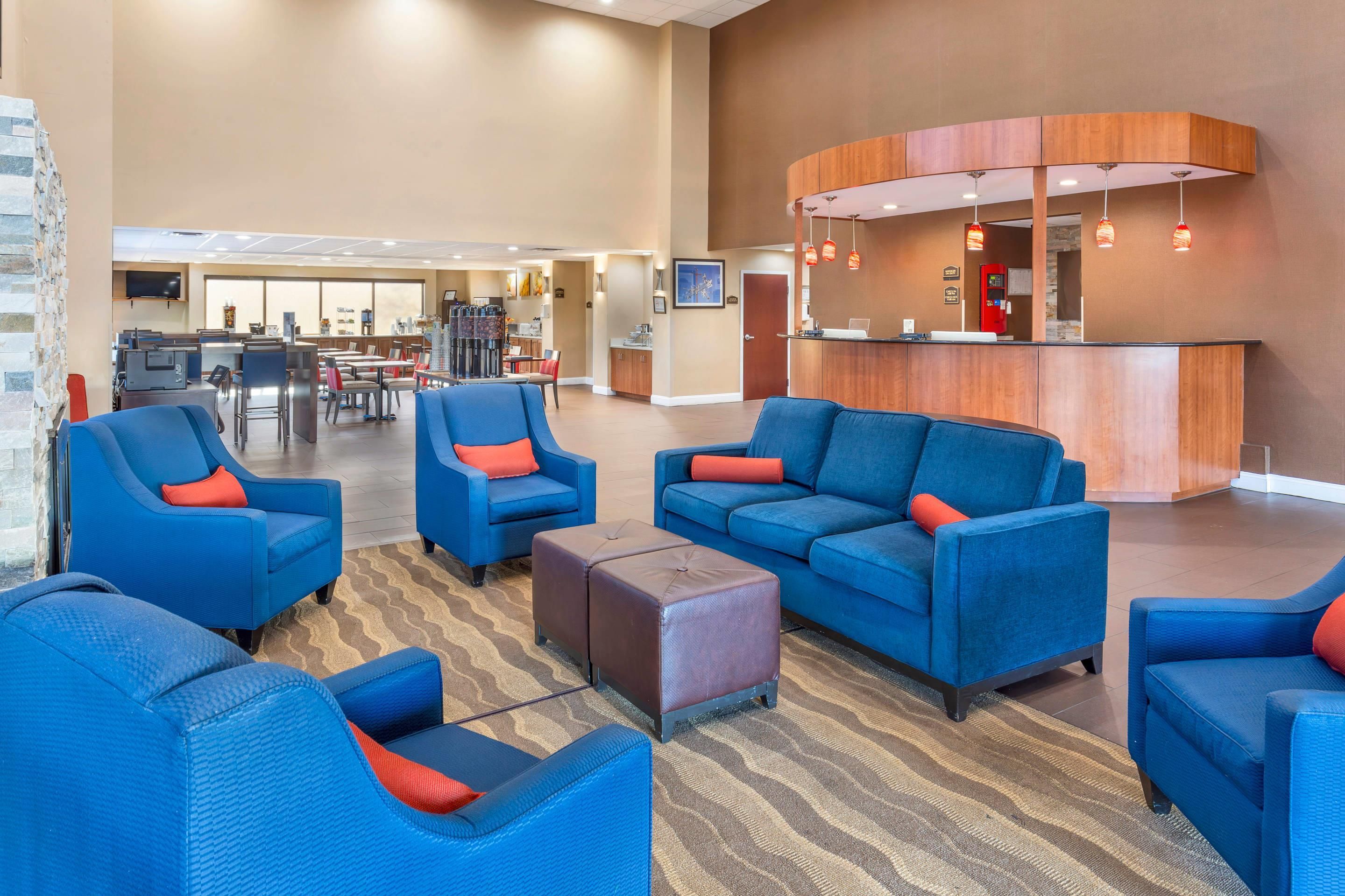 A hotel lobby with seating areas, a reception desk, and a kitchen in the background.