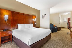 Habitación de hotel con una cama grande, lámparas de noche, un escritorio, una silla y piso alfombrado.