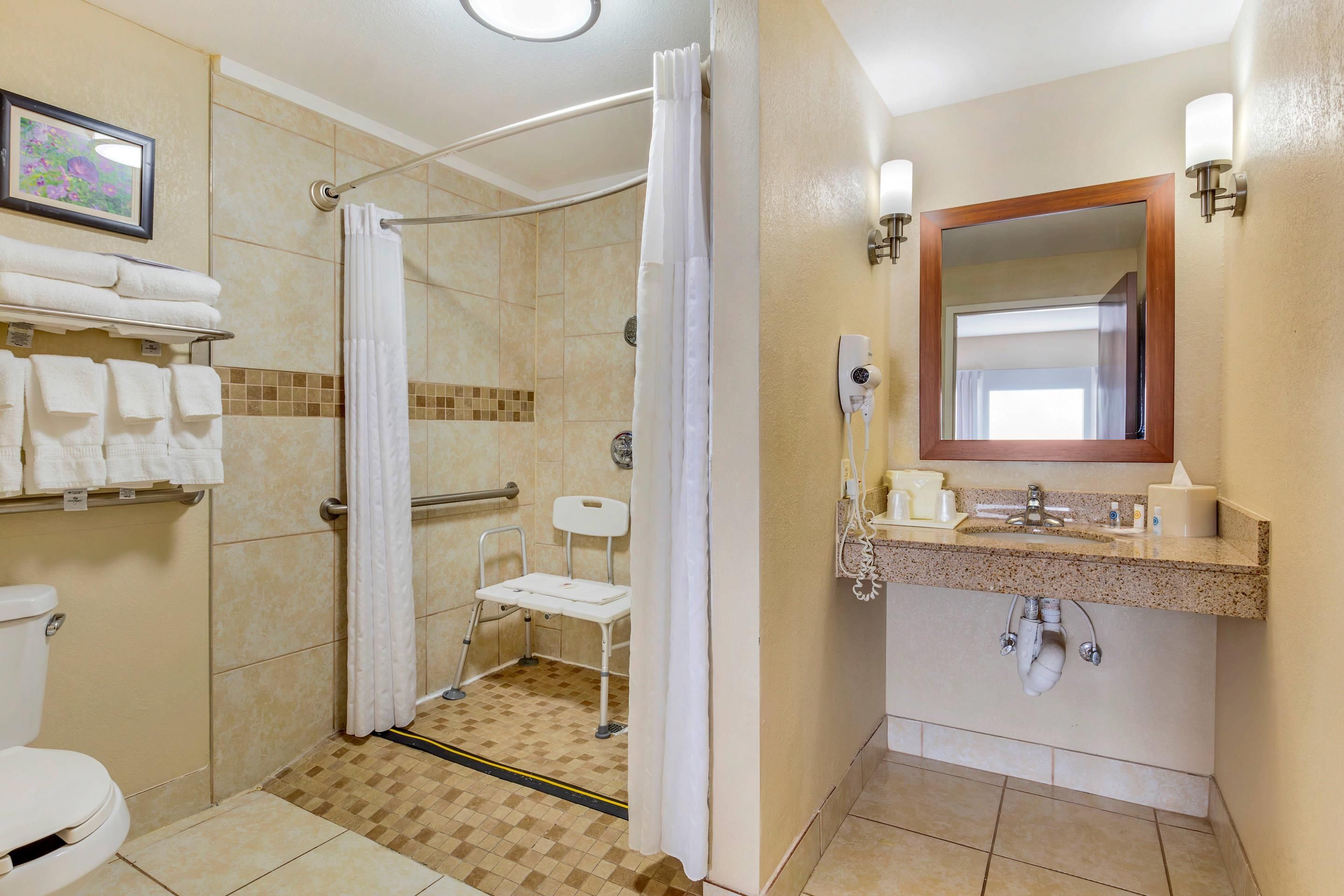 A bathroom with a shower, toilet, and sink, equipped with a hand dryer and a towel rack.