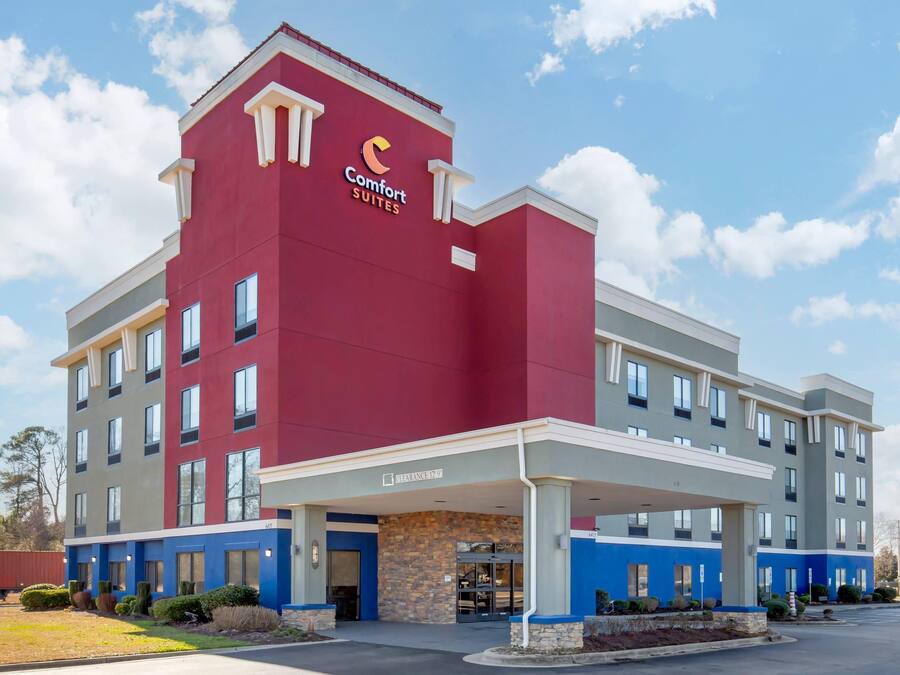 A hotel with a red and blue facade, a covered entrance, and a sign indicating a clearance of 12'9'.