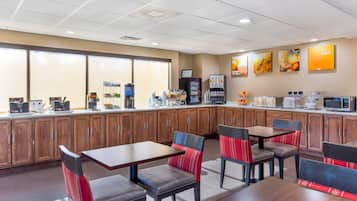 A restaurant with wooden cabinets, a counter with coffee machines, and a seating area with tables and chairs.