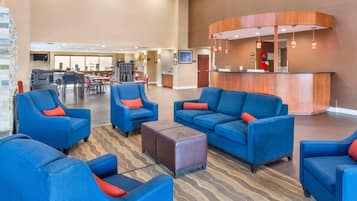 A hotel lobby with seating areas, a reception desk, and a coffee station.
