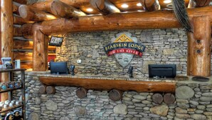Pareda de pedra com teto de toras de madeira e uma placa com a inscrição 'Bearskin Lodge on the River'.