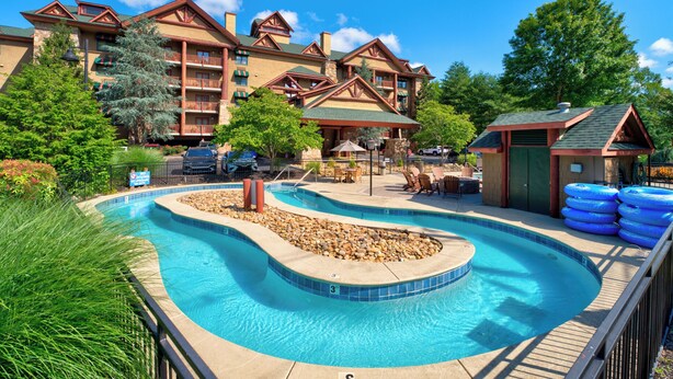 Um resort com uma piscina grande, área de estar externa e um edifício com fachada de pedra.