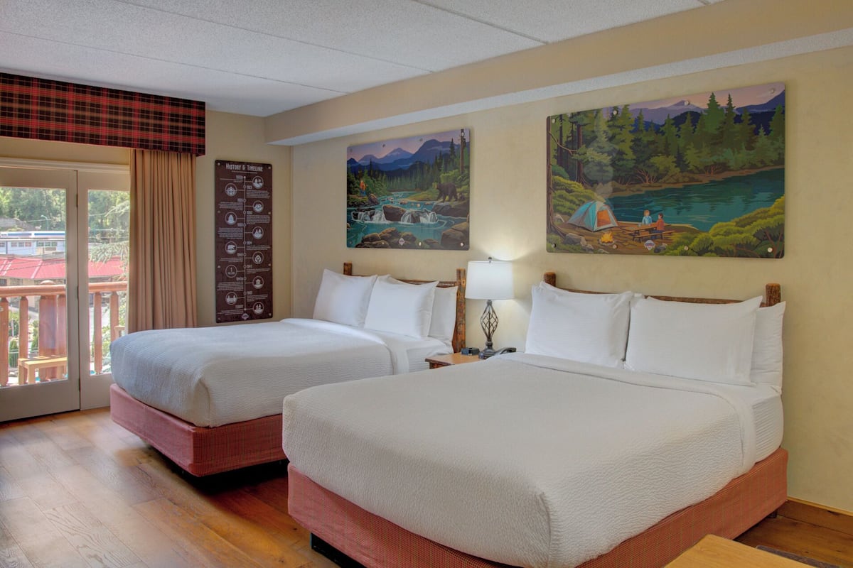 Habitación de hotel con dos camas, un balcón con vistas y una línea de tiempo en la pared.