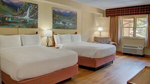 Quarto de hotel com duas camas, uma janela com cortinas e dois quadros na parede.
