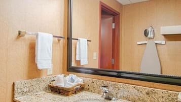 A bathroom with a granite countertop, a sink, a mirror, and a towel rack.