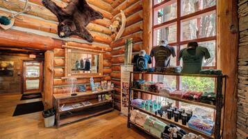 A rustic lodge interior with wooden walls, a bear skull, and a display of local products.