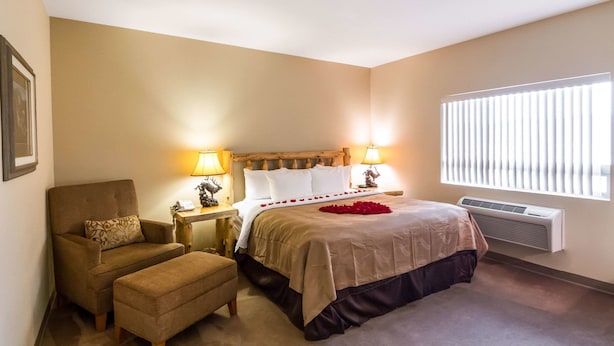 A bedroom with a bed, a chair, bedside tables, and a window with blinds. - Quality Inn Selah Yakima (Selah)
