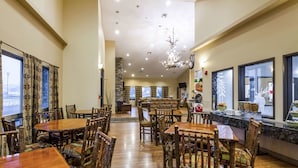 A spacious dining area with wooden tables and chairs, a chandelier, and large windows with curtains. - Quality Inn Selah Yakima (Selah)
