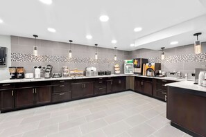 A modern kitchen with dark cabinets, a tiled backsplash, and various appliances like a coffee maker, toaster, and microwave.